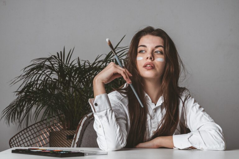 Artist sitting down with paint brush in hand