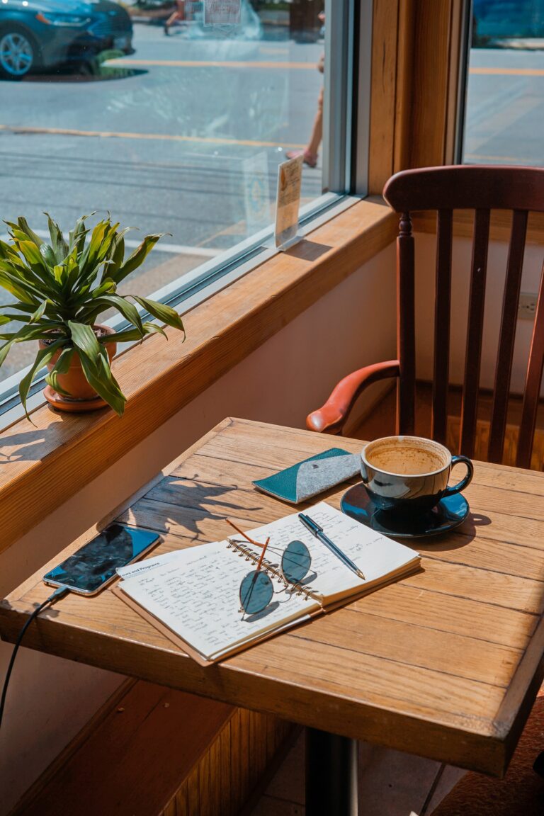 desk by the window with pad, pen and coffee and smartphone