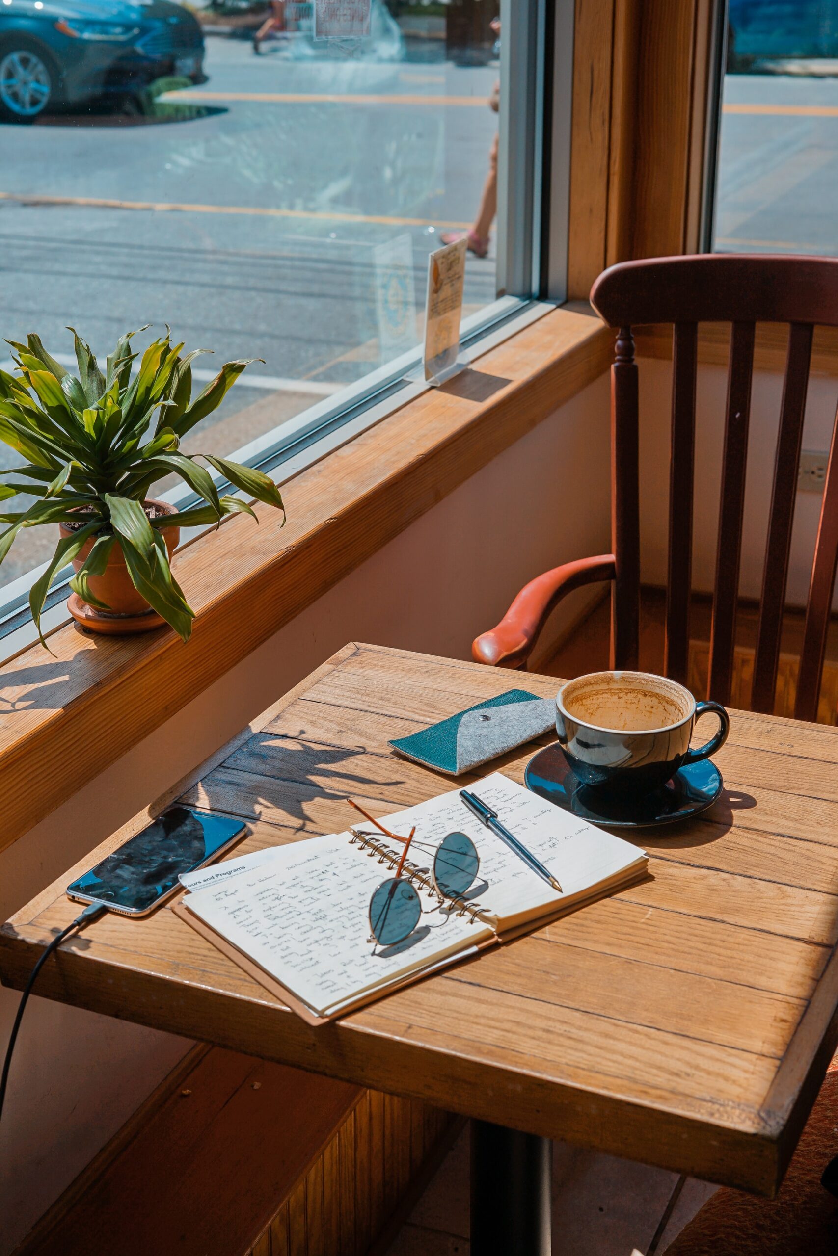 desk by the window with pad, pen and coffee and smartphone