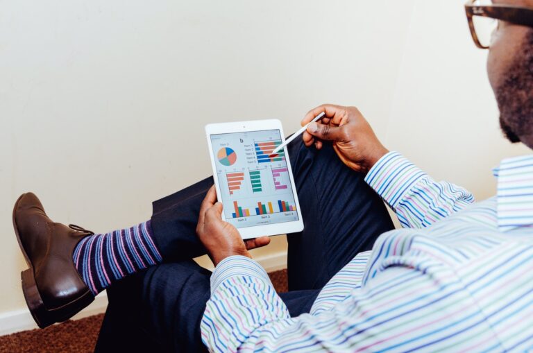 Business man looking at his ipad which is showing marketing analytics