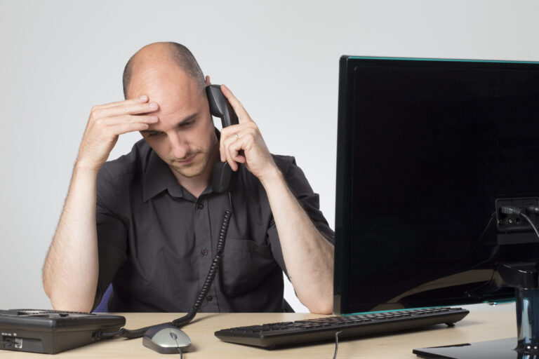 man at a desk on the phone dealing with a difficult customer