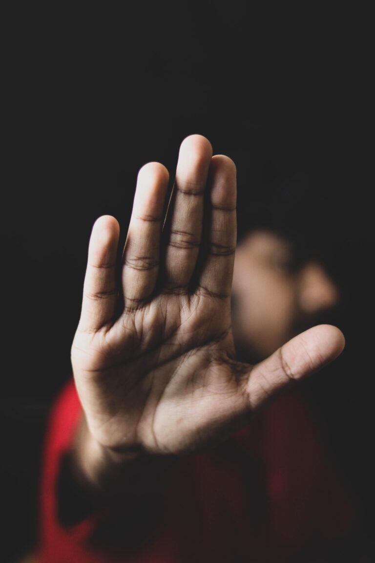 Person with their hand held up, palm outwards to say no to sexual harassment