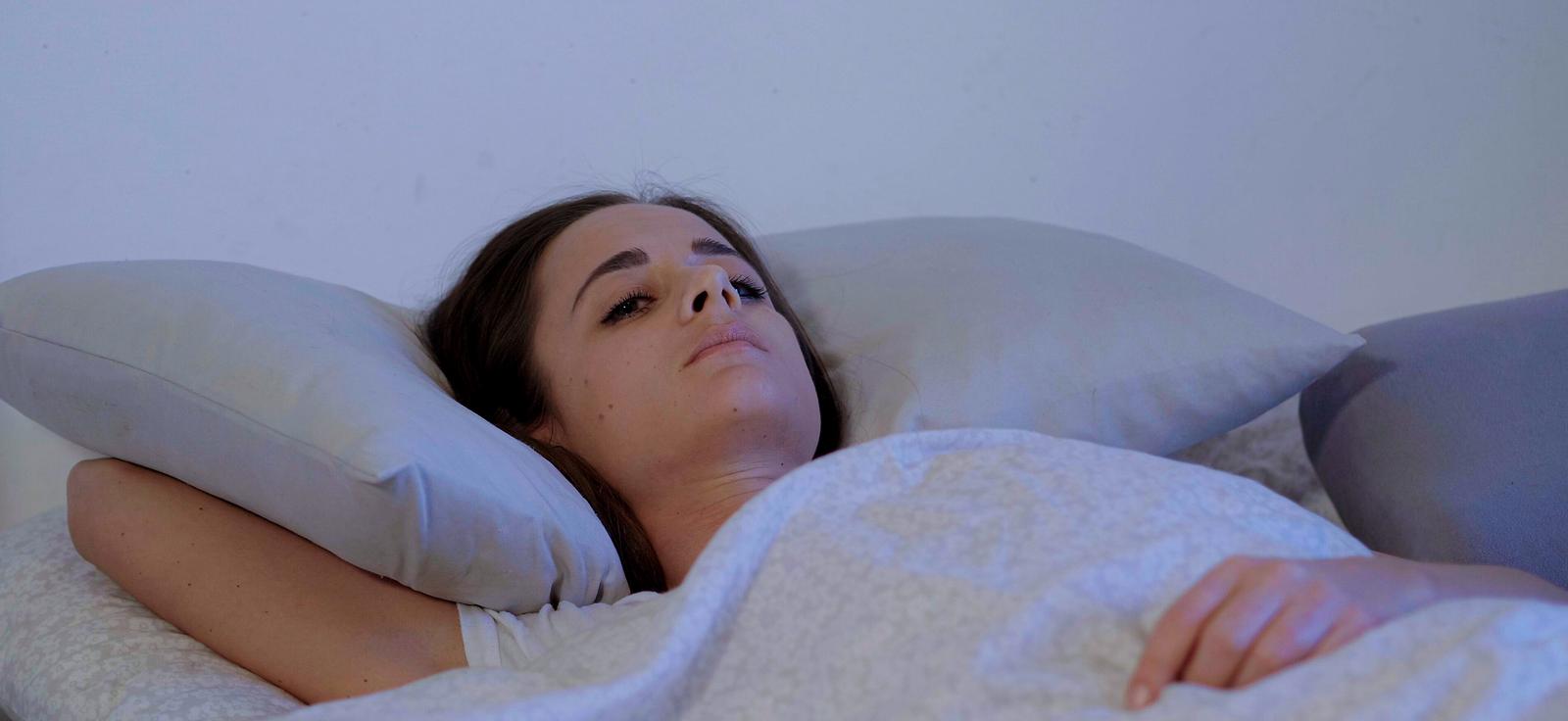 Woman lying in bed awake, looking concerned