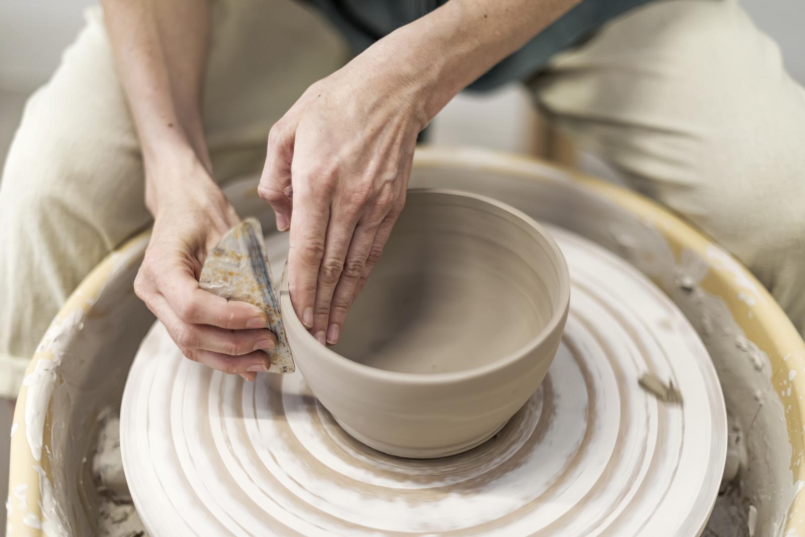 hands of person working on a pottery wheel making a bowl