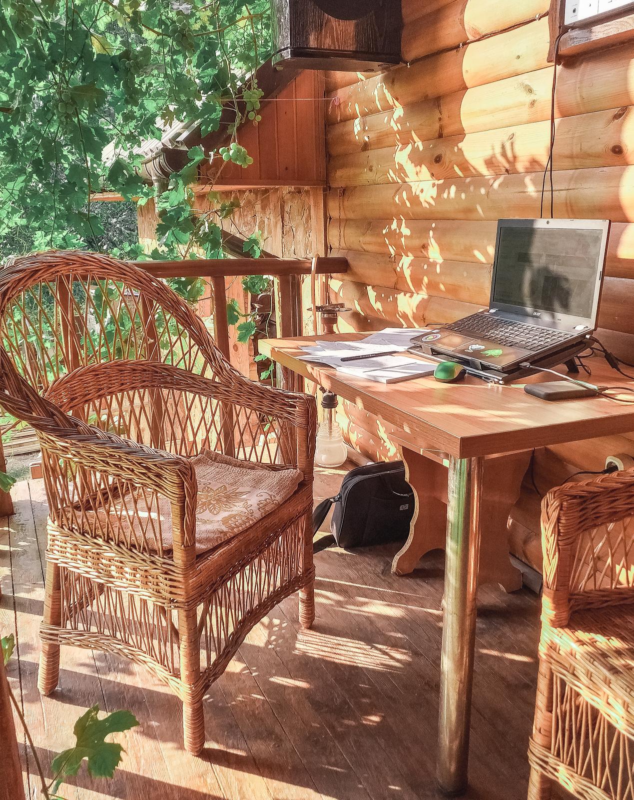 A workspace in the garden with wicker furniture and a laptop for running a side hustle
