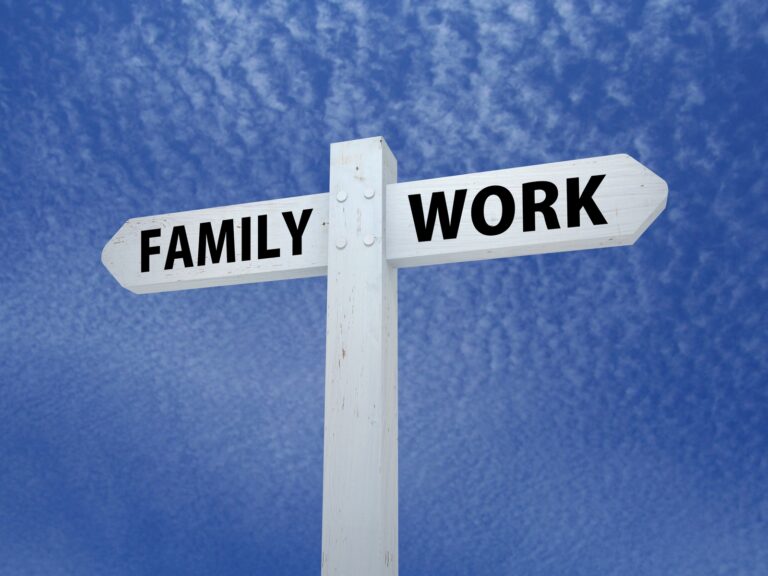 a white sign post with two arrows on a blue background. One arrow says Family the other arrow says Work