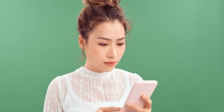 Young woman looking at her smartphone, realising her CV or Resume has been rejected.