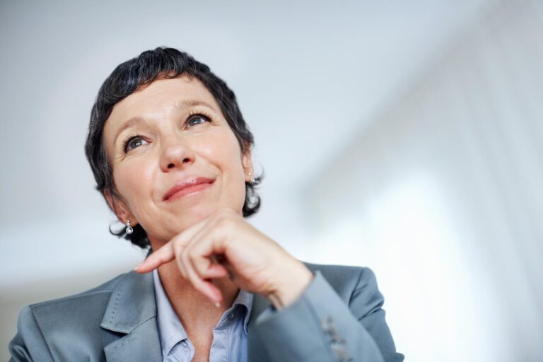 Mature executive looking up while balancing her chin on her hand to indicate thinking