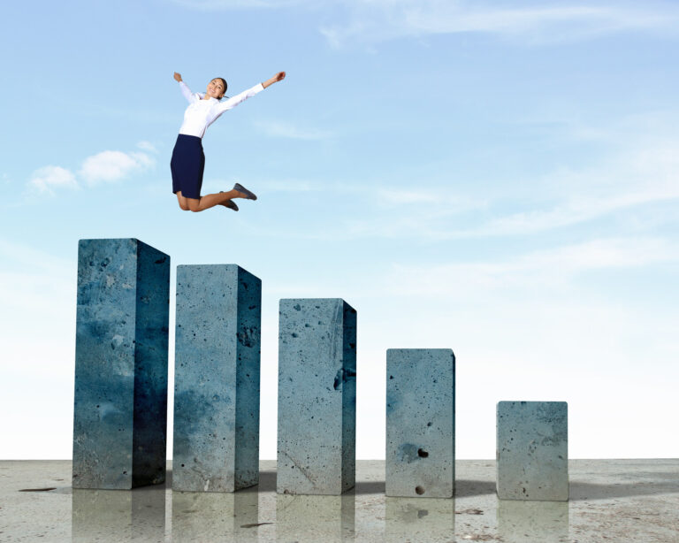 Woman jumping for joy at the top of a bar chart indicating financial success.