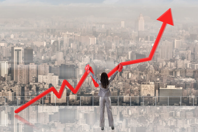 Business woman stood in front of a red arrow indicating growth with a cityscape in the background.