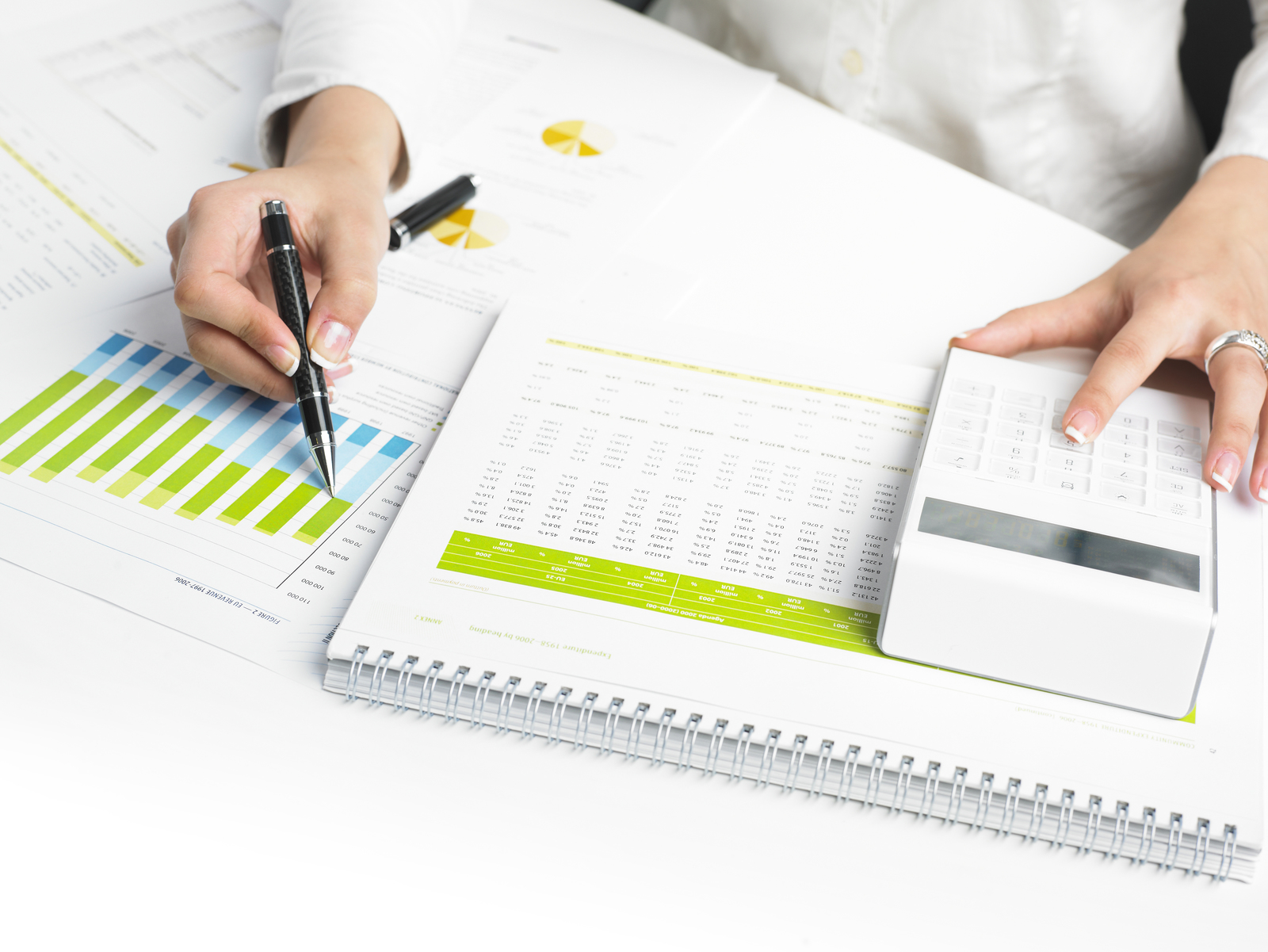 Business person sat at a table with business data and calculator in from of them analysing the finacial accounts.