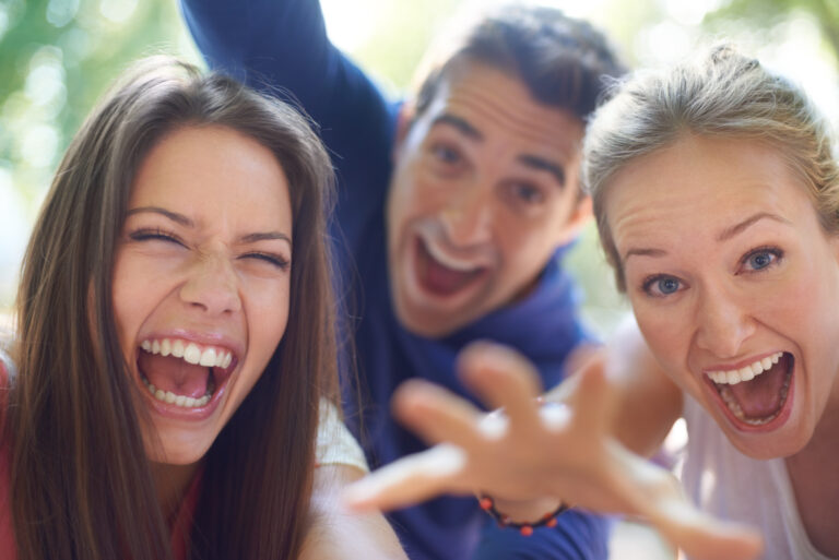 Two women and one man laughing and vying for attention.