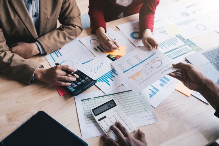 Three people sat around a table analysing data for a start up business.