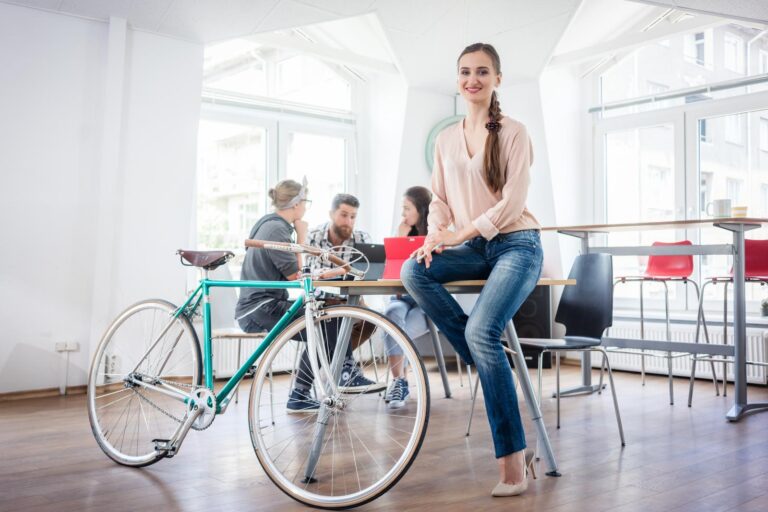 A young woman sat behind her commuter bike in a virtual office