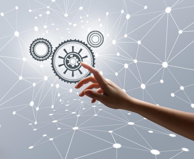 Business woman pointing to an image of cogs on a background of interconnecting nodes to illustrate business automation