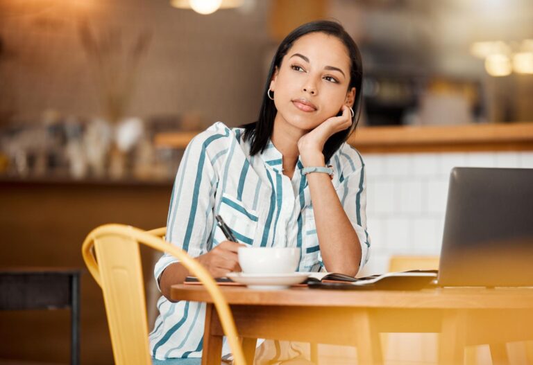 An employee sitting at a table with a coffee, thinking about job hopping for her next career move.