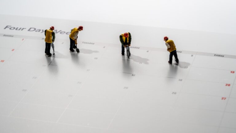 Printed calendar for a 4 day working week showing weekend days in red with small workmen working in the workweek