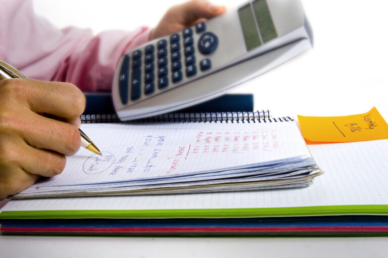 business man calculating his business finances with a pad pen and calculator.