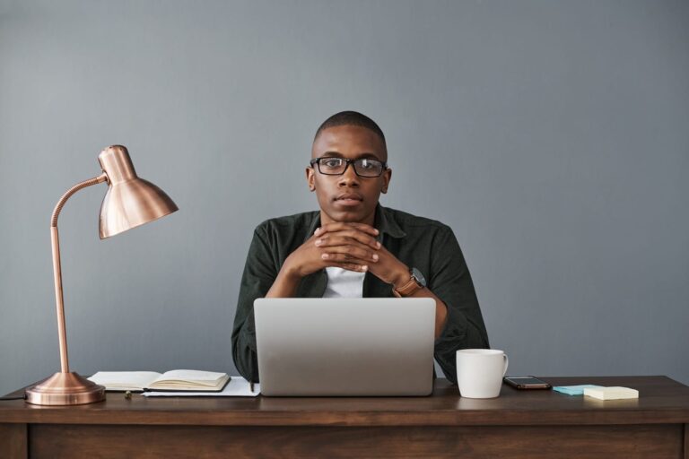 A business man sat behind a laptop on a desk working from home