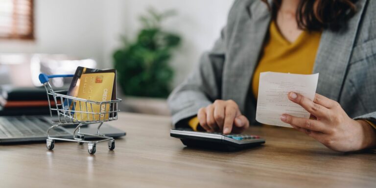 Register for VAT early. A woman sat at a desk calculating VAT with a calculator.