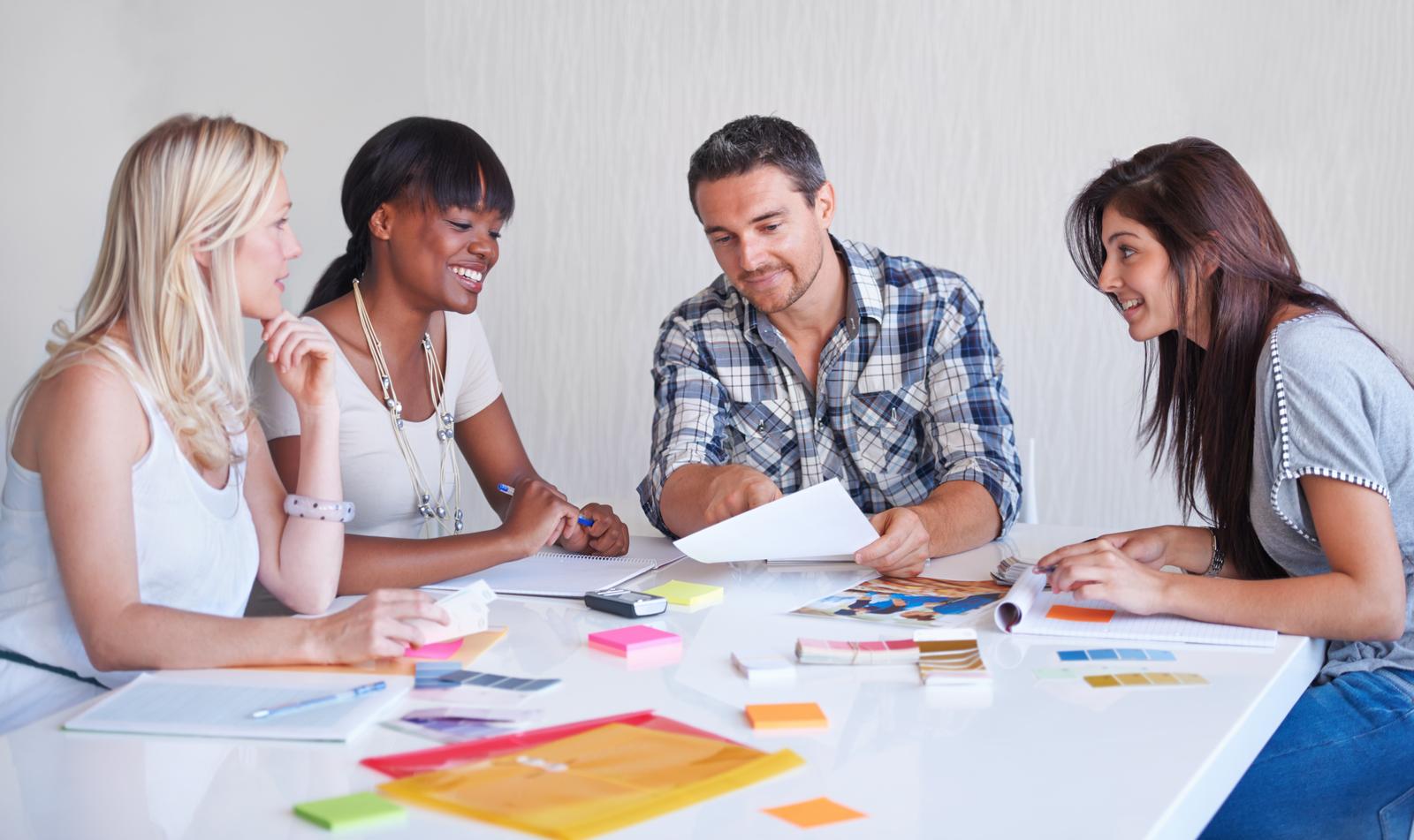 three women and one man sat around a table with Post It stickers, brainstorming ideas for the business name.