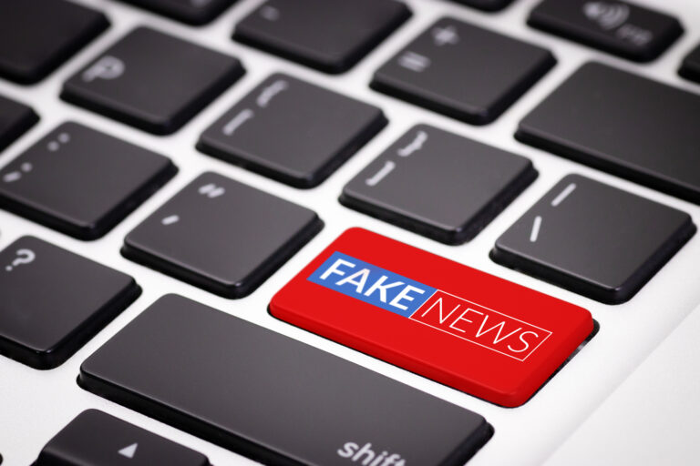 keyboard with red return key with the words Fake News