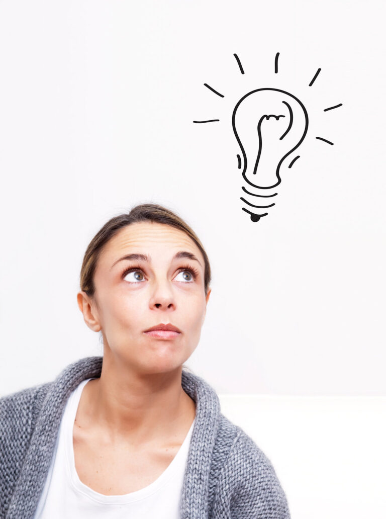 Woman thinking of business ideas looking up at a sketch of a lightbulb