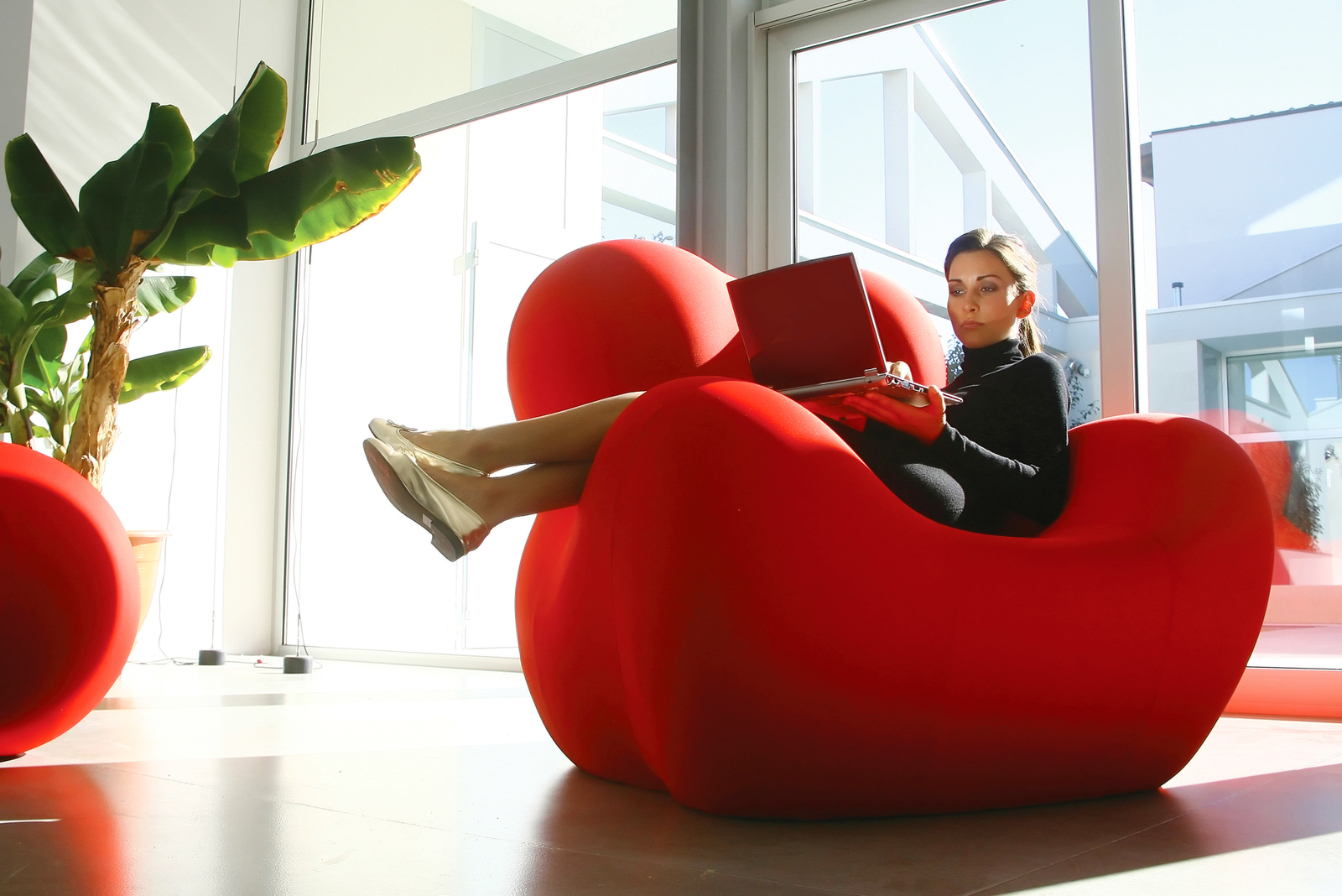 Business woman in a red seat using her laptop to create a CV for the ATS