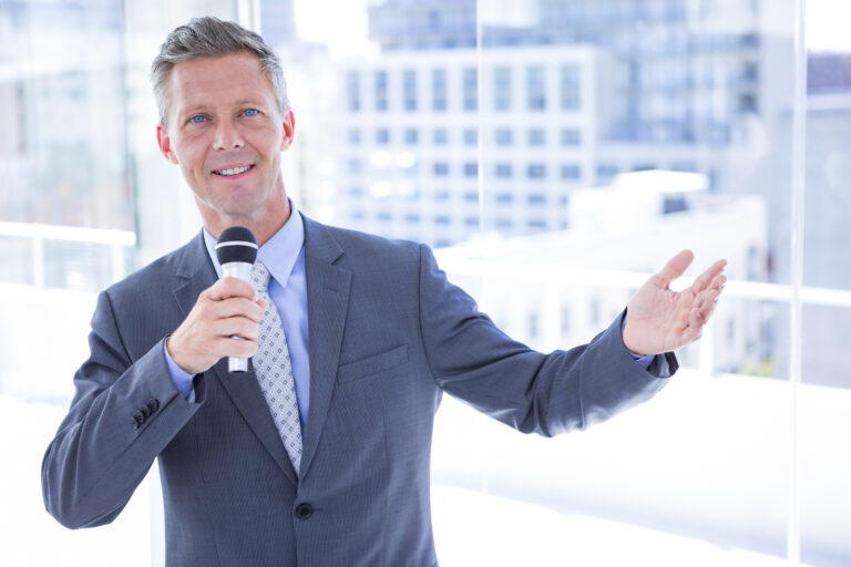 Business man with mic, telling his story of success to an audience.