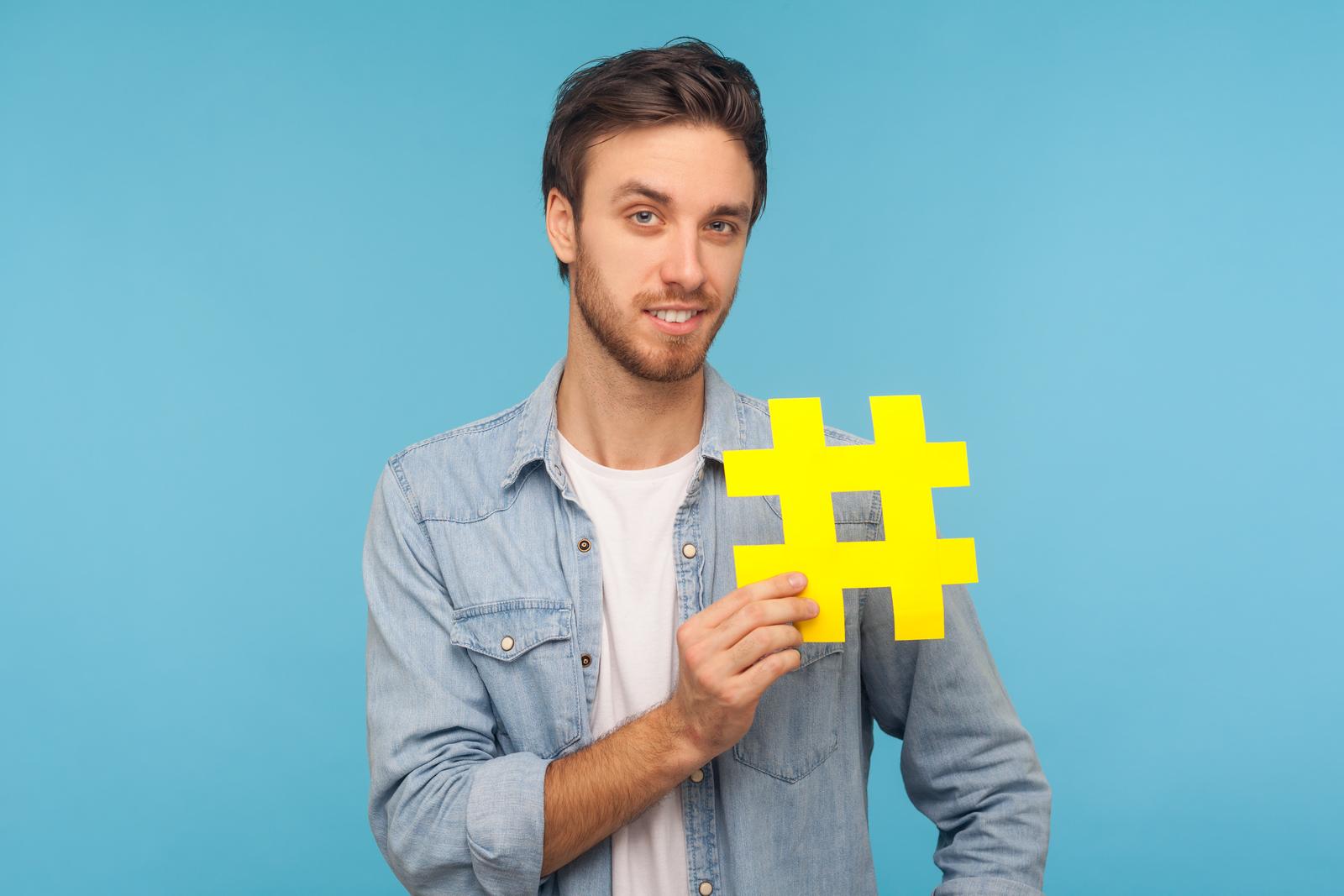 Young entrepreneur holding up a paper hashtag